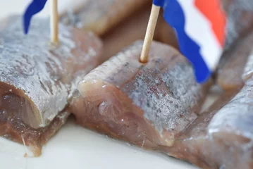 Fototapeten Den Helder, Netherlands. June 2022. Close up of raw herring with dutch flag and onions. © Bert