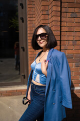 brunette girl in a blue jacket and jeans walks through the city streets