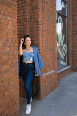 brunette girl in a blue jacket and jeans walks through the city streets