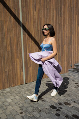 brunette girl in a blue jacket and jeans walks through the city streets