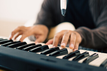 Fototapeta premium Close up hands songwriter playing piano keyboard and guitar in home studio. Professional musician audio equipment at Recording studio.