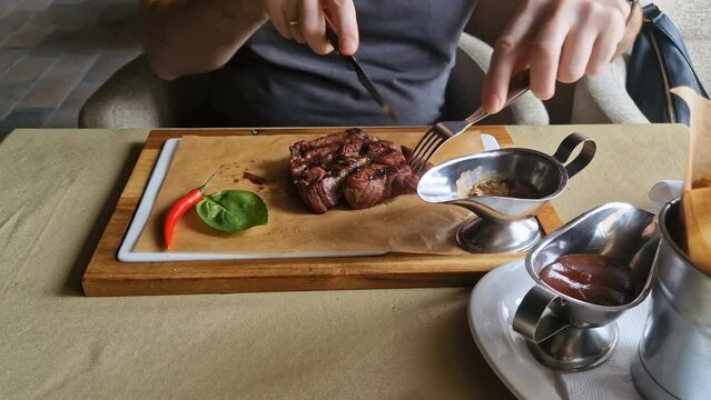 A man cuts a marble ribeye steak in a restaurant.