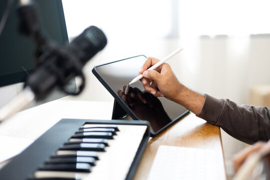 Close up hands song writer composing music note on tablet. Professional composer Recording Mixing and Mastering in home studio with keyboard and guitar. Digital music production