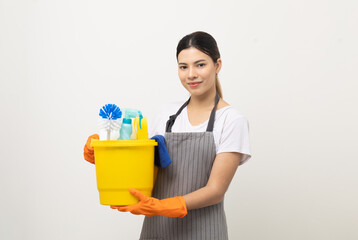 Young housekeeper woman holding bucket of cleaning products ready for cleaning home on isolated white background.