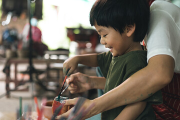 Happy family moment Mother teaching son how to painting mug cup ceramic workshop. Child creative activities and art. Kid playing  pottery workshop. Developing children's learning skills.