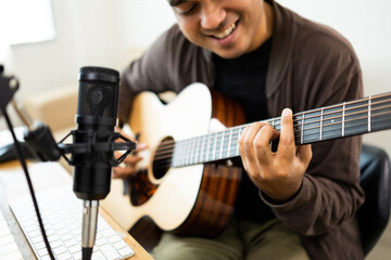 Professional Musician with condenser microphone and tablet for Mixing Mastering music. Hispanic male composing a song with guitar and piano keyboard at digital Recording home studio - obrazy, fototapety, plakaty