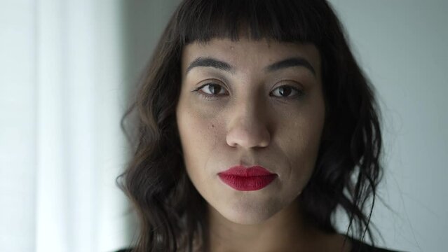 One South American woman with serious expression portrait face wearing red lipstick looking at camera