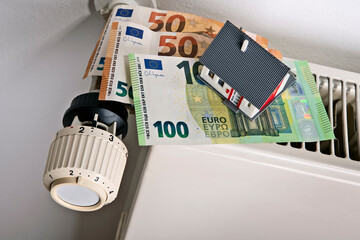 Radiator and thermostat with euro banknotes and house as symbol for rising heating costs