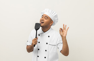 Super star singing masterchef. Young happy asian chef wearing uniform enjoy with singing voice and dancing in the kitchen on isolated white background. Indian man Occupation restaurant and hotel.