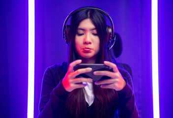 Stressed Boring Young pretty asian woman in headphone playing game. Chinese female Gamer holding cell phone play video game online feeling sadness. Loss and Missed the chance to become a champion