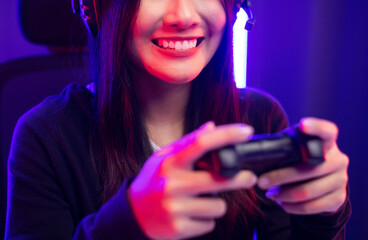 Close up hands Playing video game. Young pretty woman holding joystick controller console. Female Professional Streaming playing game online in dark room neon light. © Chanakon
