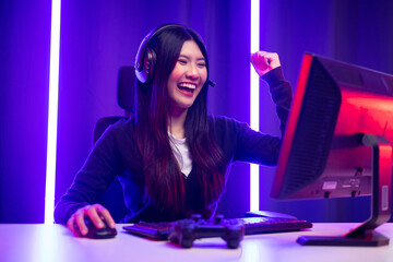 Professional gamer. Young asian pretty woman sitting on chair with computer pc in living room....
