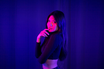 Stylish sexy woman in trendy. Beautiful young asian woman standing pose with neon light. Asia Pretty asian female in the dark room. Fashion shot.