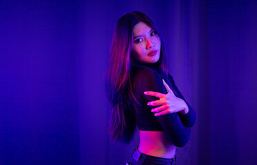 Stylish sexy woman in trendy. Beautiful young asian woman standing pose with neon light. Asia Pretty asian female in the dark room. Fashion shot.