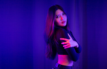 Naklejka premium Stylish sexy woman in trendy. Beautiful young asian woman standing pose with neon light. Asia Pretty asian female in the dark room. Fashion shot.
