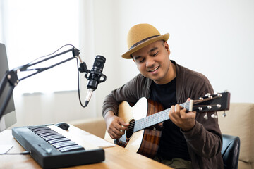 Obraz premium Professional Musician with condenser microphone and tablet for Mixing Mastering music. Hispanic male composing a song with guitar and piano keyboard at digital Recording home studio