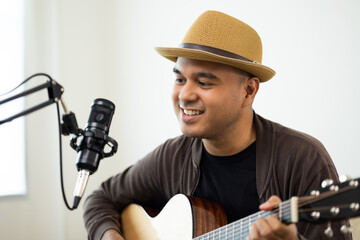 Lifestyle concept. Young asian musician playing guitar in living room at home on this weekend....