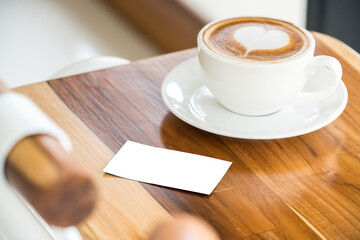 empty business card mock up with hot coffee on wood table.blank card with white paper for insert text and graphics.