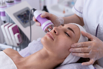 A young woman undergoing a facial radiofrequency face lift treatment. Facial skin care treatment,...