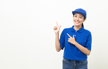 Happy delivery asian woman in blue uniform standing pointing the finger to blank space for text advertise on isolated white background. Smiling female delivery service worker.