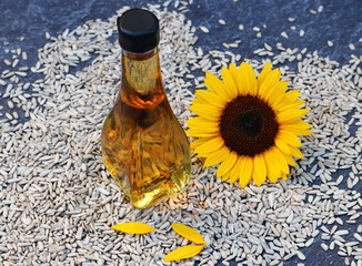 Sonnenblumenöl in einer Flasche mit Blume und vielen Sonnenblumenkernen.