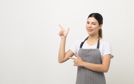 Young Beautiful Woman With Apron Standing On Isolated White Background Pointing Finger To Blank Space. Housekeeping Housework Or Maid Worker Concept.