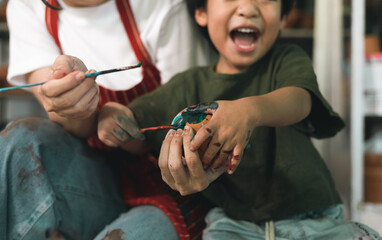 Happy family moment Mother teaching son how to painting mug cup ceramic workshop. Child creative activities and art. Kid playing  pottery workshop. Developing children's learning skills.