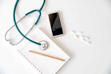 Stethoscope medical equipment with blank notebook mobile phone and painkiller medicine.