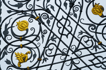 Fototapeta na wymiar Cast iron fence, Gate or Doorway rich with decor in gold. Made in old Baroque styke. Close up