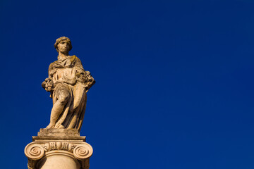 Fototapeta na wymiar Abundantia, ancient roman goddess of abundance, wealth, money, prosperity, fortune, and success. A 15th century statue erected in the Pisa historical center (with blue sky and copy space)