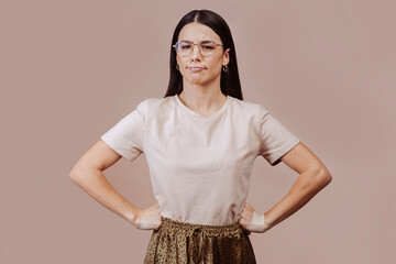 Waist-up portrait of beautiful girl with brunette straight hair in displeasure, wears beige...