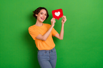 Photo of pretty adorable young lady wear orange outfit rising heart like sign isolated green color background