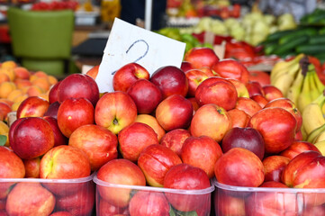 aFresh nectarines for sale at fruit market, close up. Boxes full of nectarines and apricots with prices in shop.  