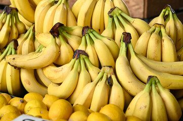 Fresh bananas for sale at fruit market, close up. Boxes full of raw peaches with price in shop. 