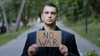 Serious strong caucasian adult man activist standing outdoors demonstrating cardboard plate with...