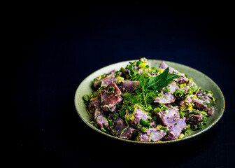 Fototapeta na wymiar Vegan potato salad made with blue potatoes, fresh herbs and tahini