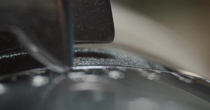 Close up view of tailor thinning leather piece with leather skiving machine passing for making shoes in workshop background, slow motion 4k