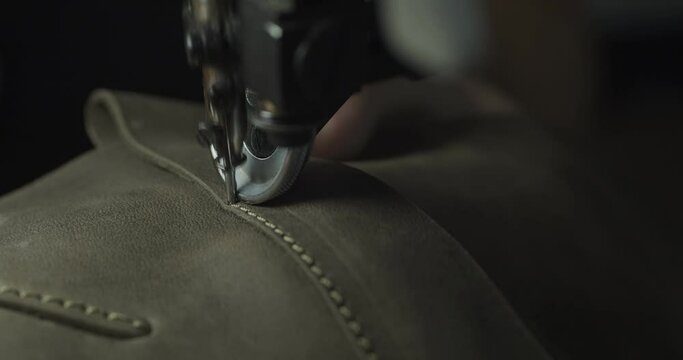 Tailor works on sewing machine in private leather craftshop, making shoes in process. male seamstress sewing leather shoes in leather workshop in 4k