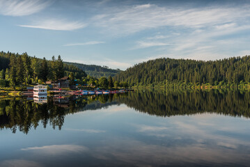 Early morning at Schluchsee in the Black Forest, water reflection, boat rental and shipping pier in...