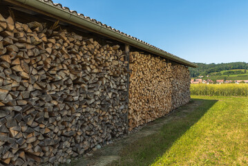 Wood pile, firewood, stacked and cut wood is stored in an open shed