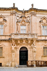 Fototapeta premium Facade of a beautiful old building, decorated with ornaments and statues. Malta, Mdina, Europe.