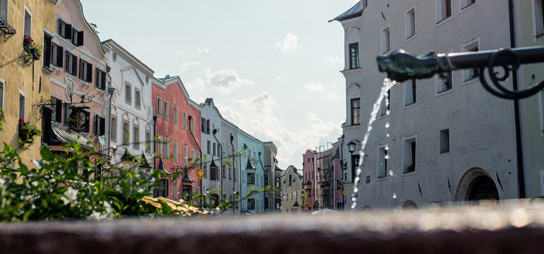 Fountain and central street in Rattenberg Austria, flowing water close-up, colorful houses in background, shallow depth of field