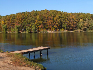 Pier on the shore of the lake around the beautiful autumn nature