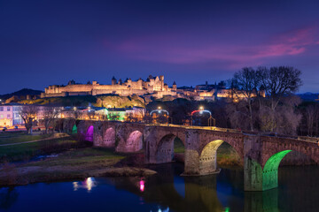 Medieval city of Carcassonne Pont Vieux bridge lit up at night during Christmas with pink clouds...