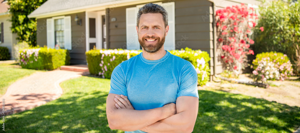 Wall mural amazed unshaven guy crossed hands near house, realtor. Man face portrait, banner with copy space.