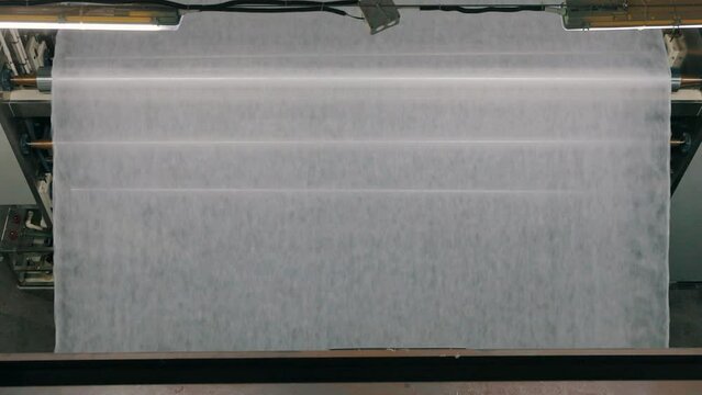 Large roll of synthetic winterizer. Syntepon manufacturing process. Industrial interior.