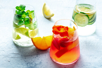 Summer cocktails. Cold drinks with fresh fruits. Healthy mocktails. Citrus, strawberry and cucumber lemonades with an edible flower