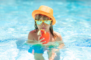 Child boy drinking summer coctail in the pool.