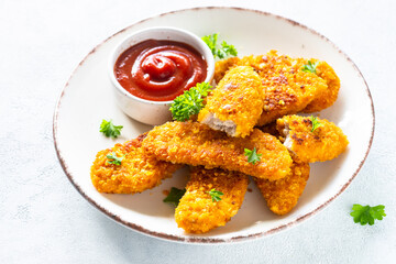 Chicken nuggets with ketchup sauce at white table.