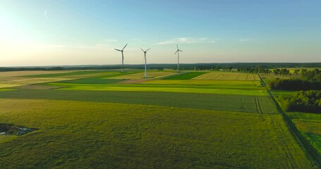 Aerial drone view of wind power turbines, part of a wind farm. Wind turbines on green field in countryside. Wind power plant.. - Powered by Adobe